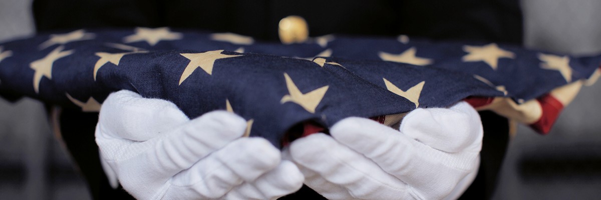 Hands of a soldier holding a folded American flag